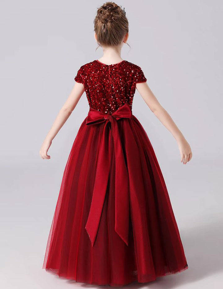 a little girl wearing a red dress with a bow