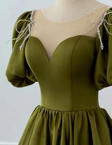 a woman wearing a green dress with a beaded neckline