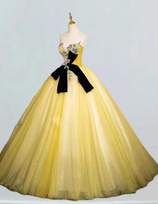 a yellow dress with a black bow on it